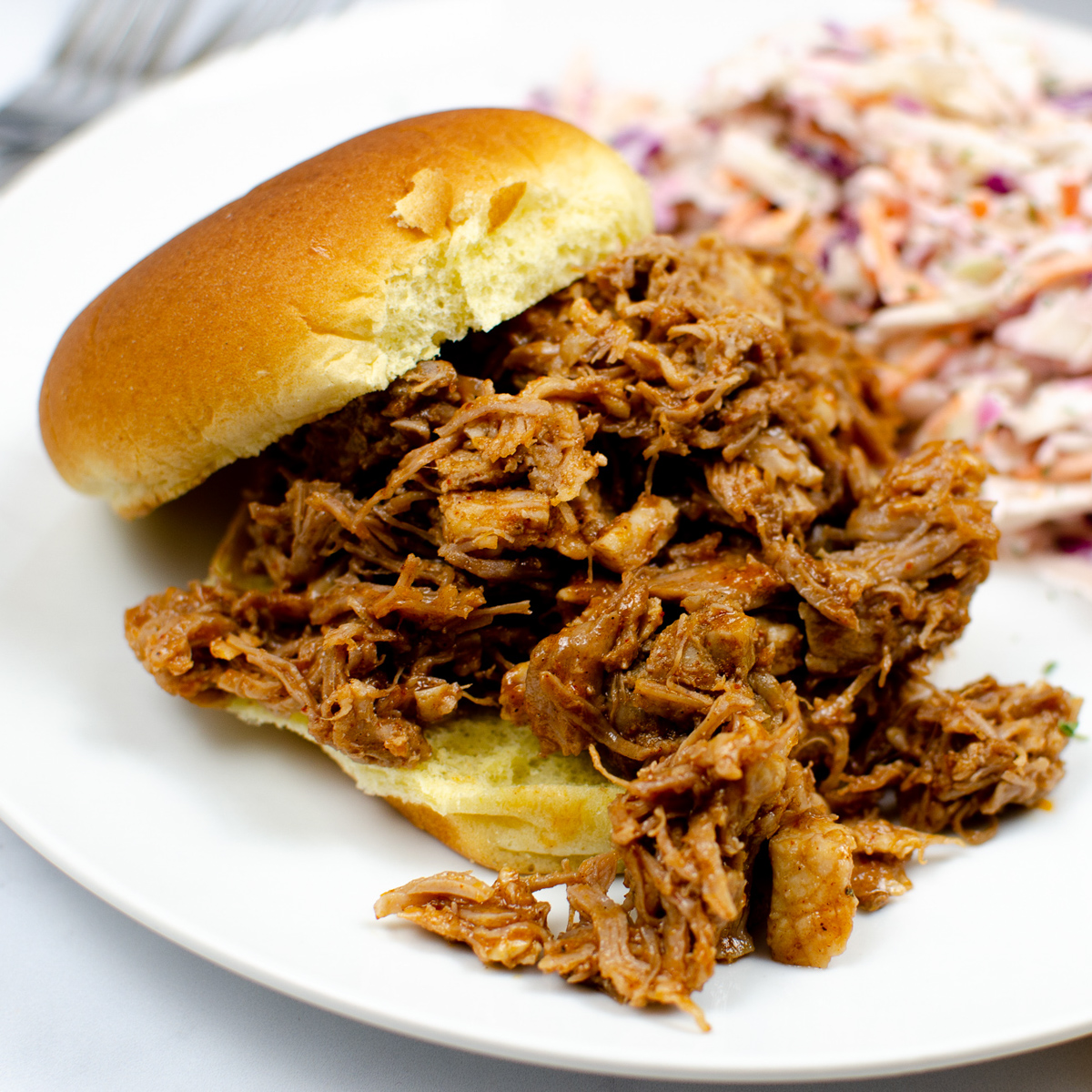 BBQ pulled pork sandwich with coleslaw in the background