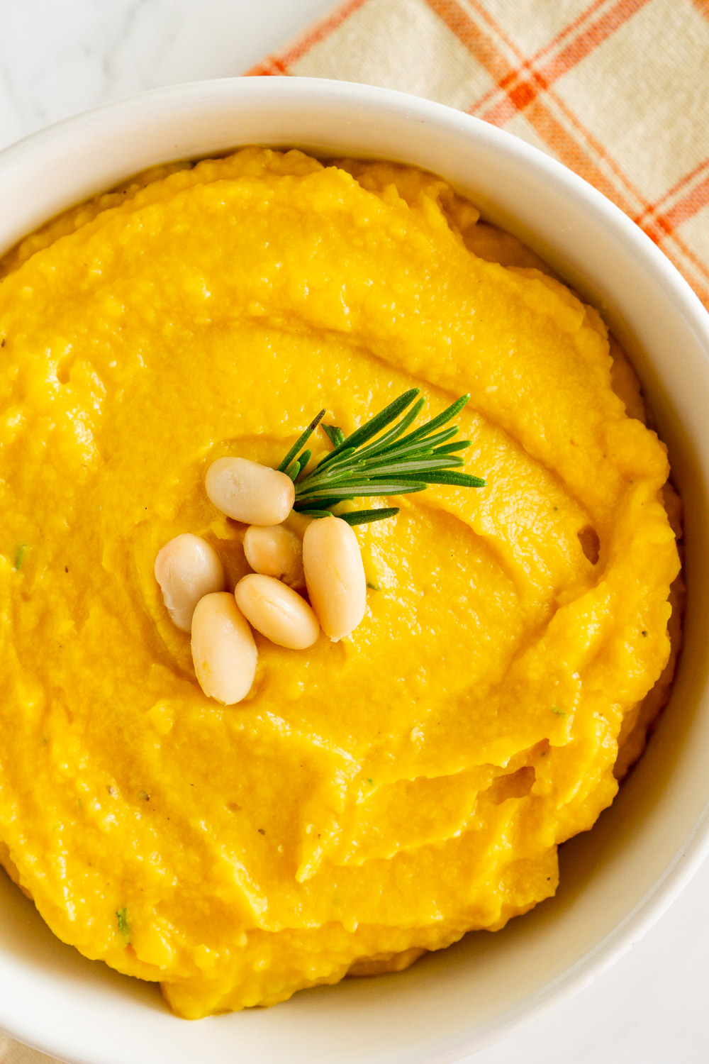 overhead image of butternut squash puree with white beans in a white bowl
