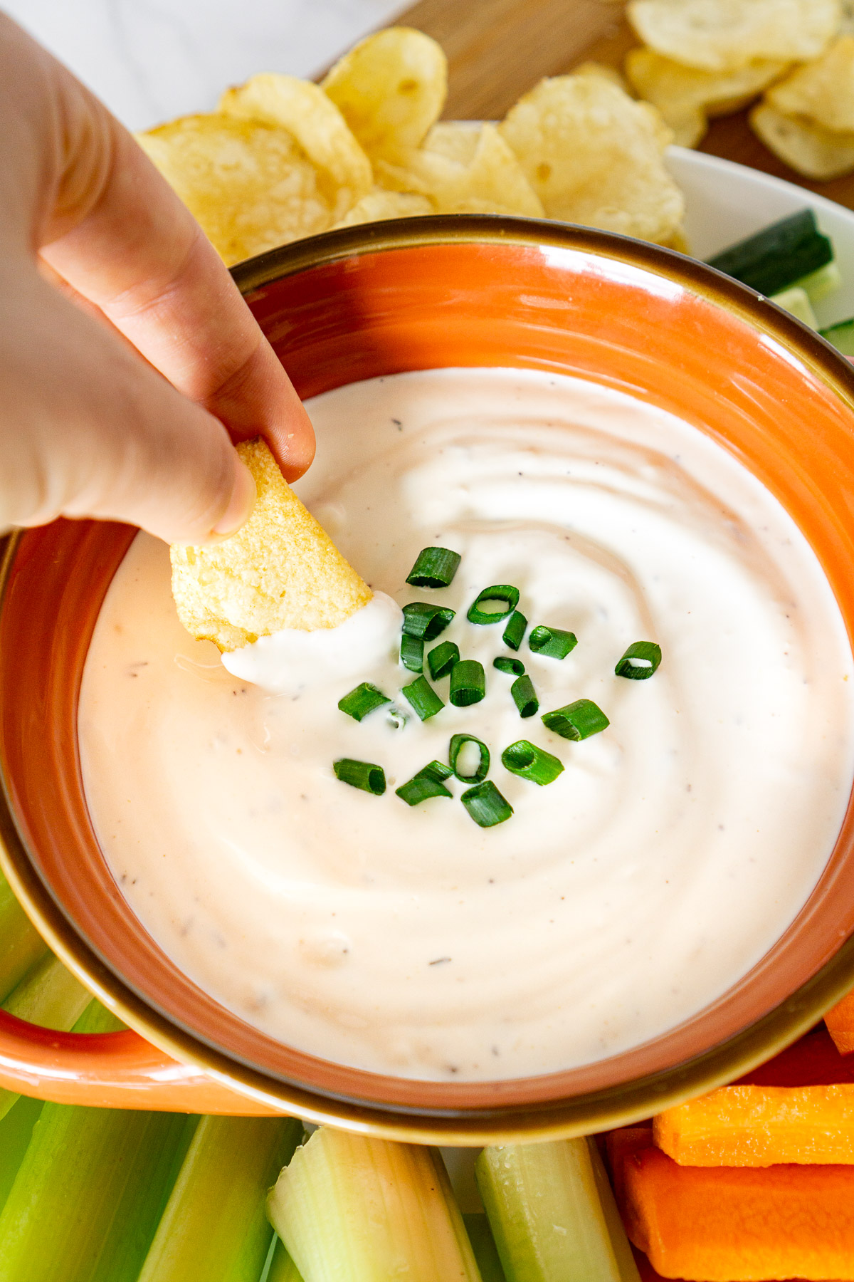 hand dipping chip into a roasted garlic chip dip
