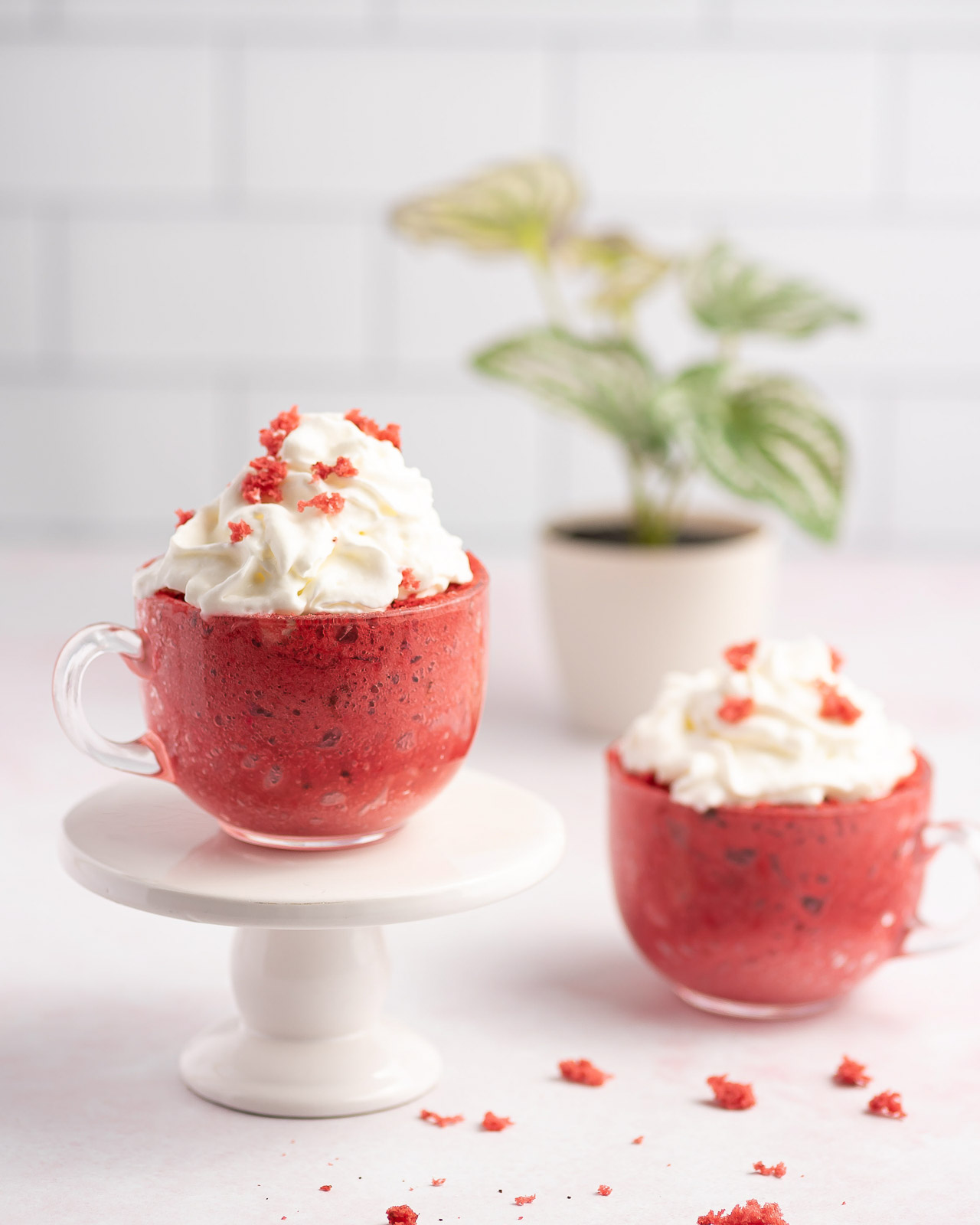 2 red velvet mug cakes topped with whipped cream on a counter