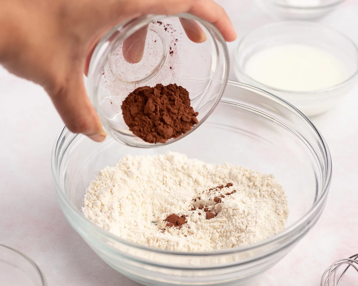 adding cocoa powder to red velvet mug cake ingredients bowl