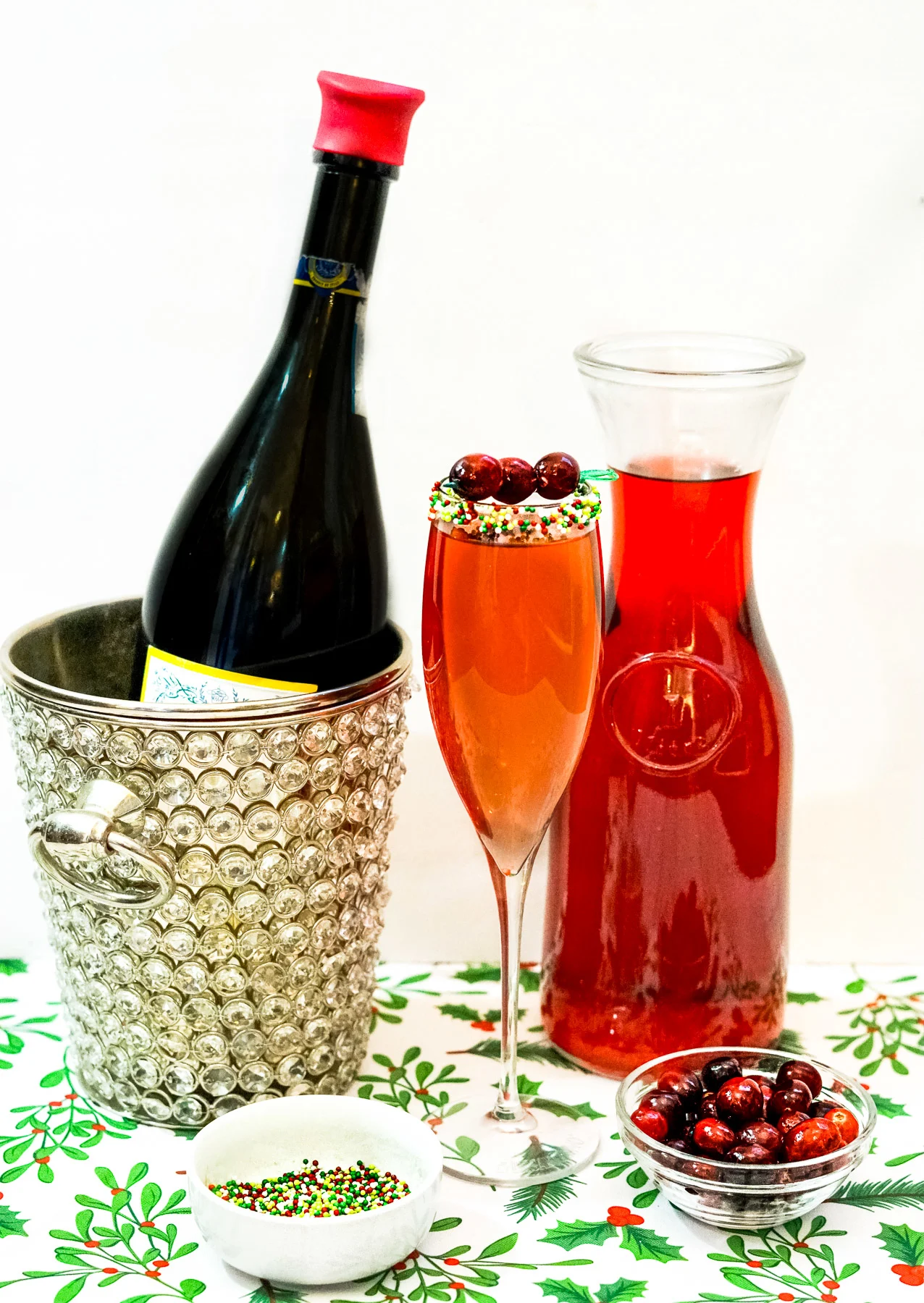 Cranberry Prosecco Cocktail next to cranberry juice and bottle of prosecco