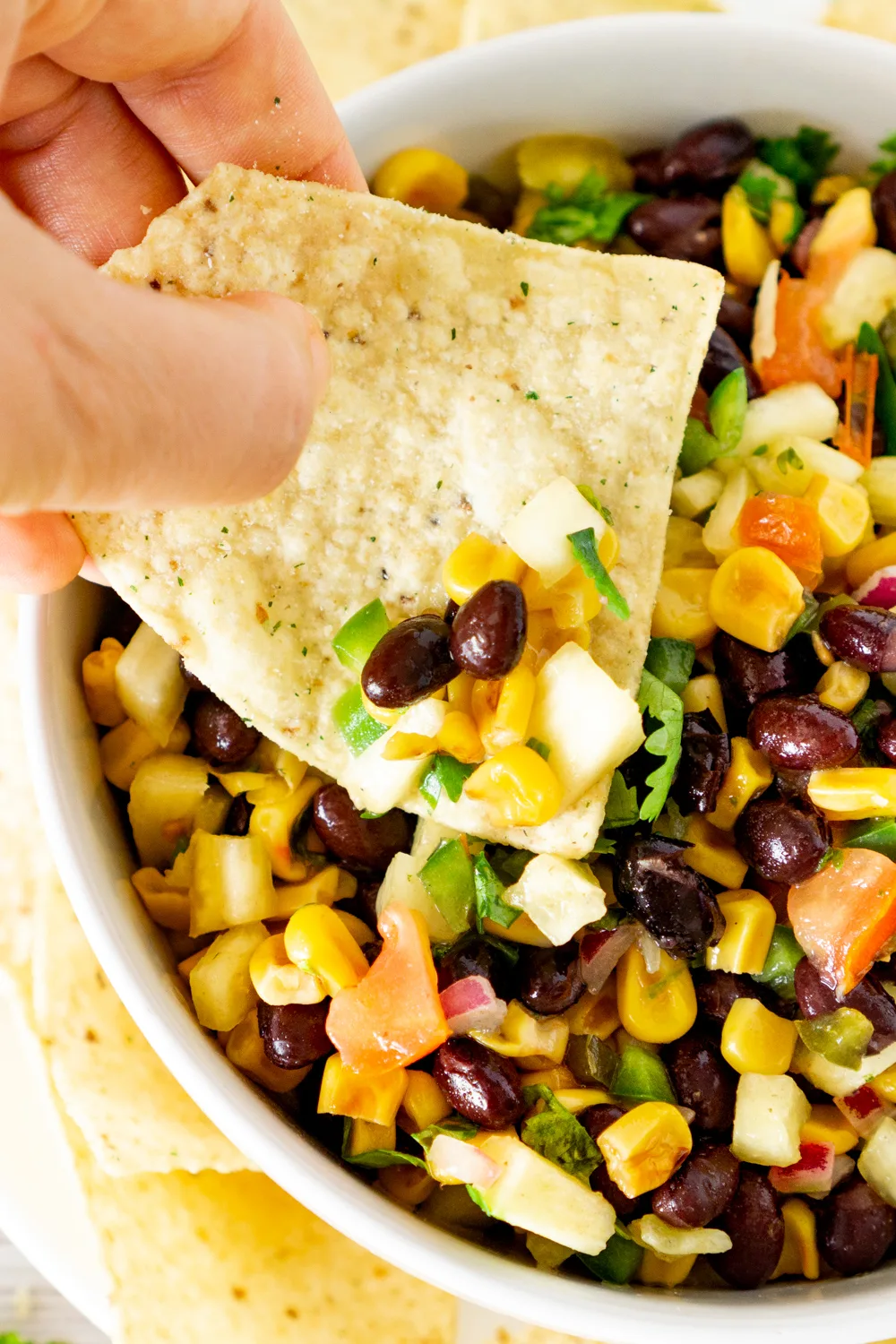 chip dipping into pineapple salsa with black beans