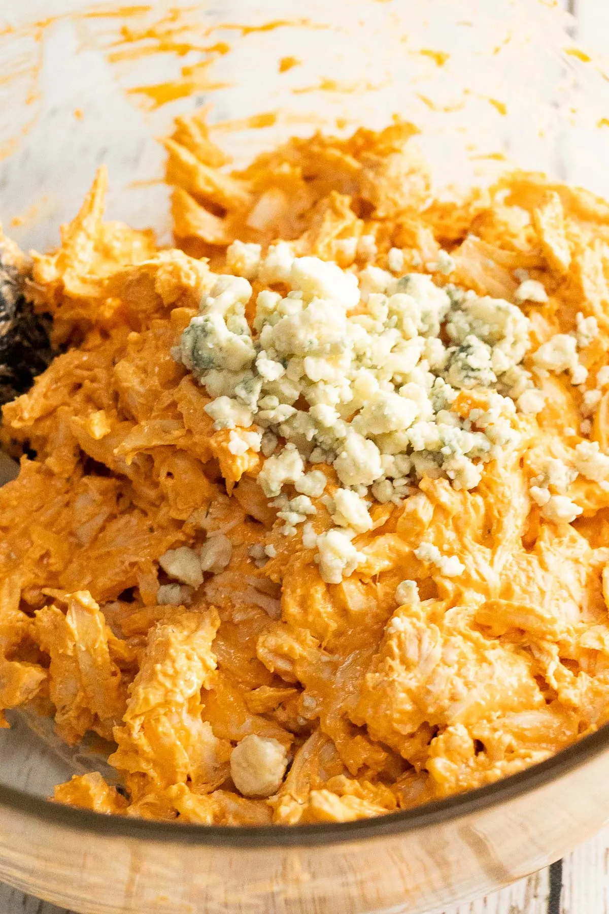 adding blue cheese and shredded chicken to the buffalo sauce mixture