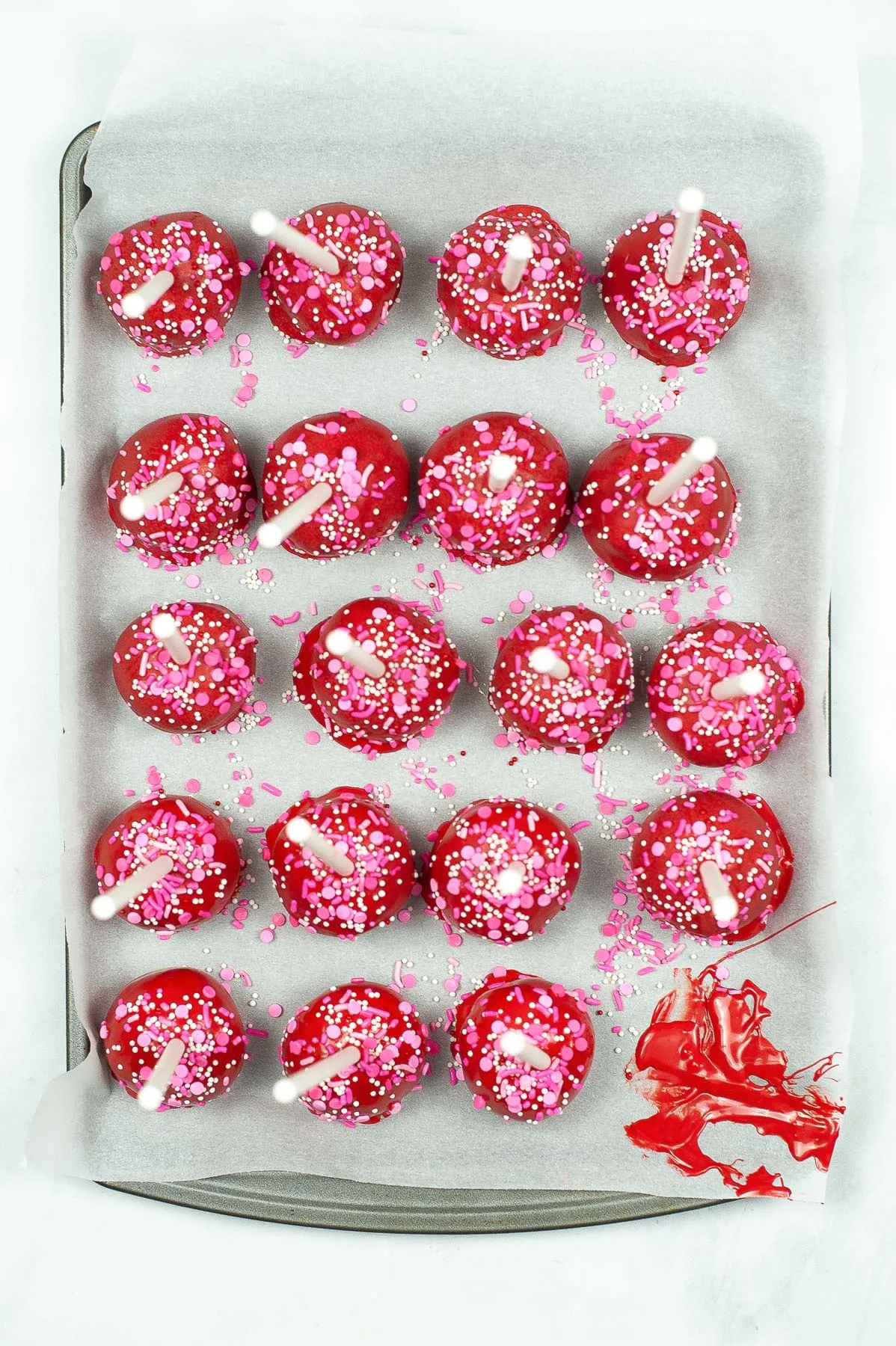red cake pops drying on parchment paper