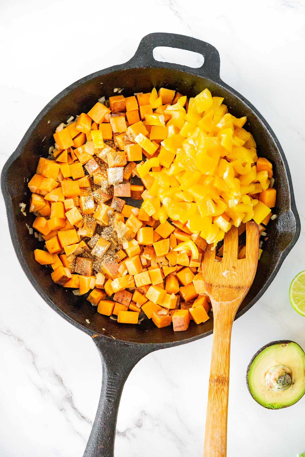 added diced bell pepper and seasonings to cubed sweet potato in a skillet