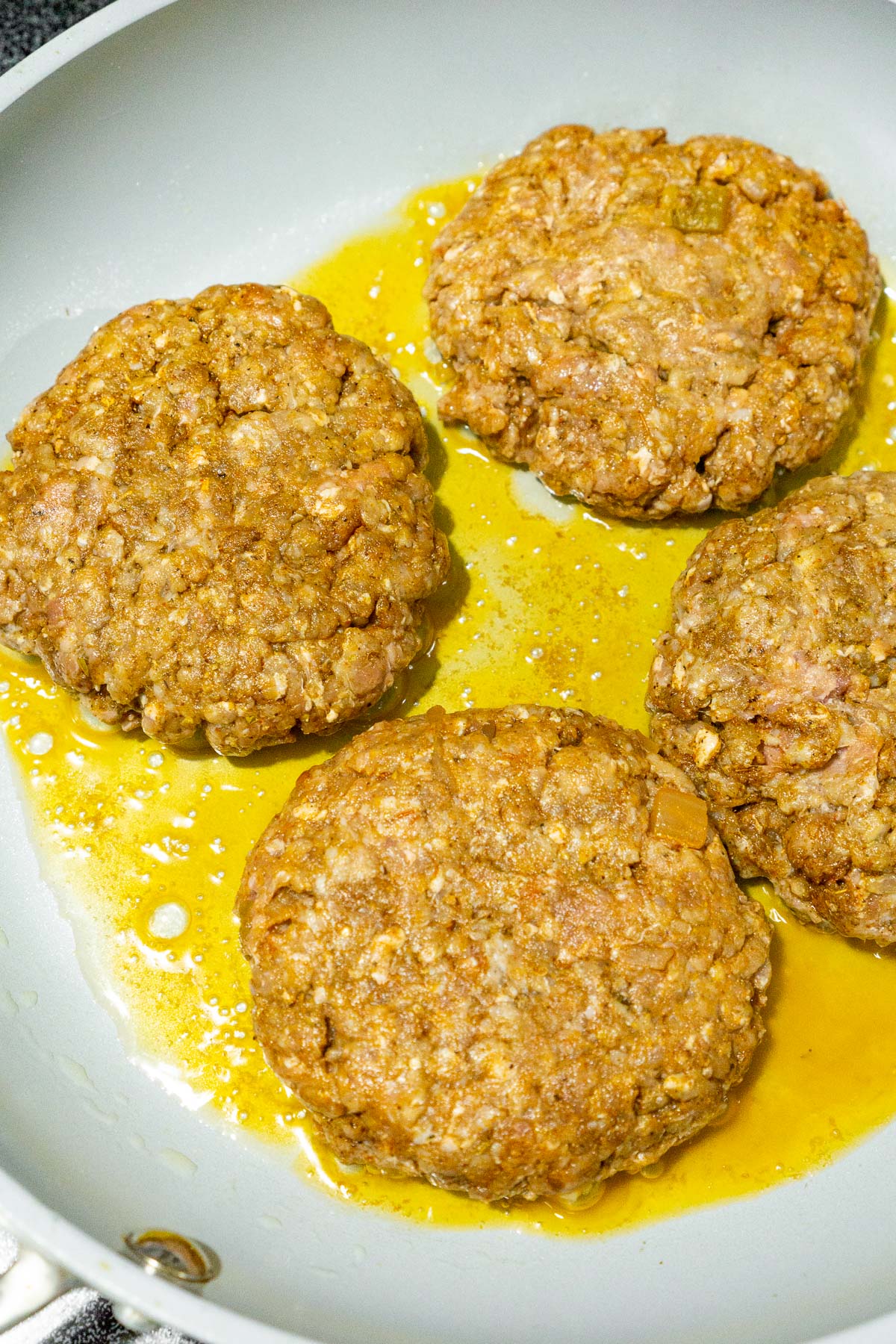 4 taco burgers with salsa cooking in a skillet