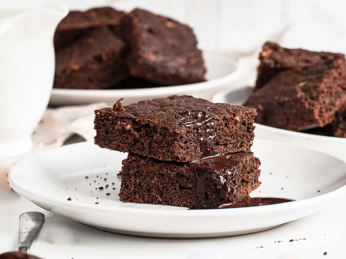 Stack of 2 zucchini brownies on a plate.