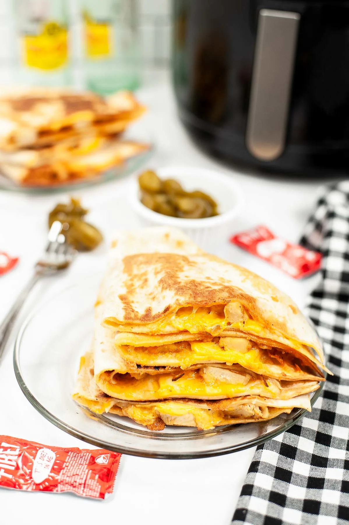 Taco bell chicken quesadilla on a plate next to air fryer and garnish.