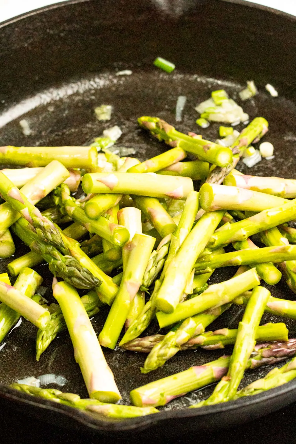 Sautéing asparagus in a pan.