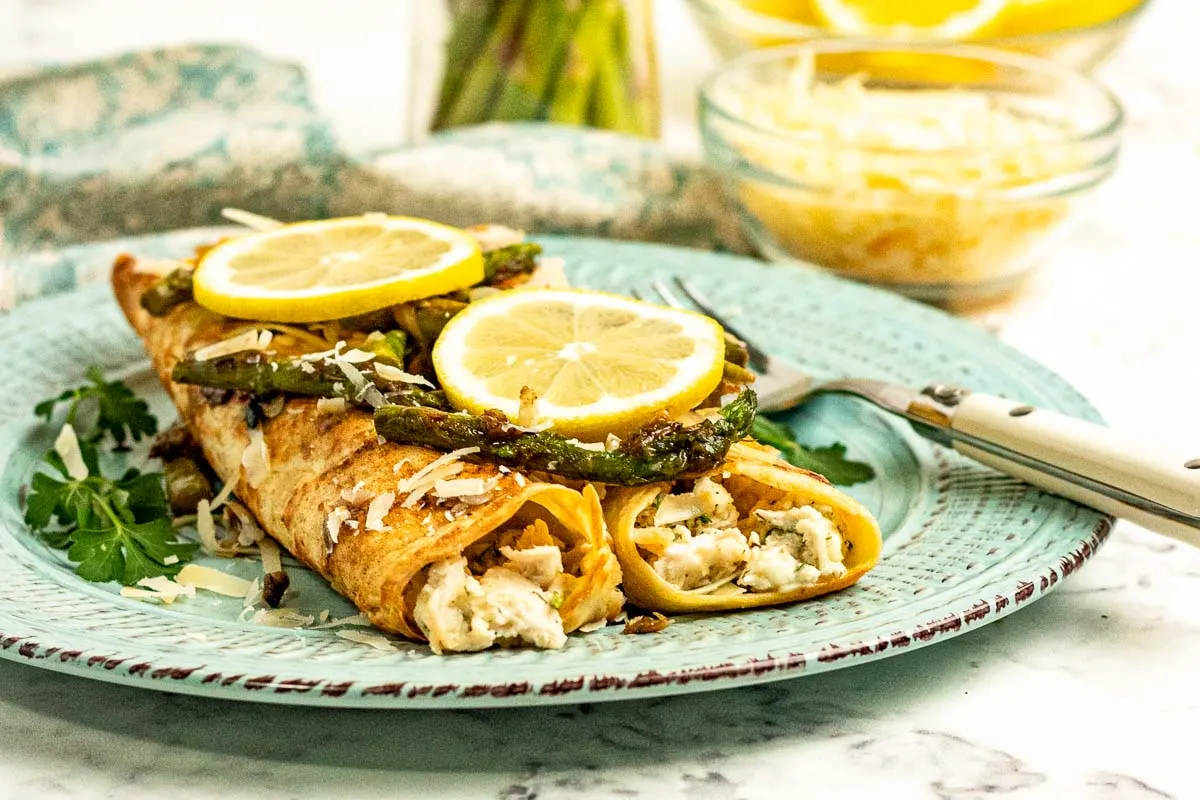 Savory crepes stuffed with chicken, served with asparagus and lemon slices. 