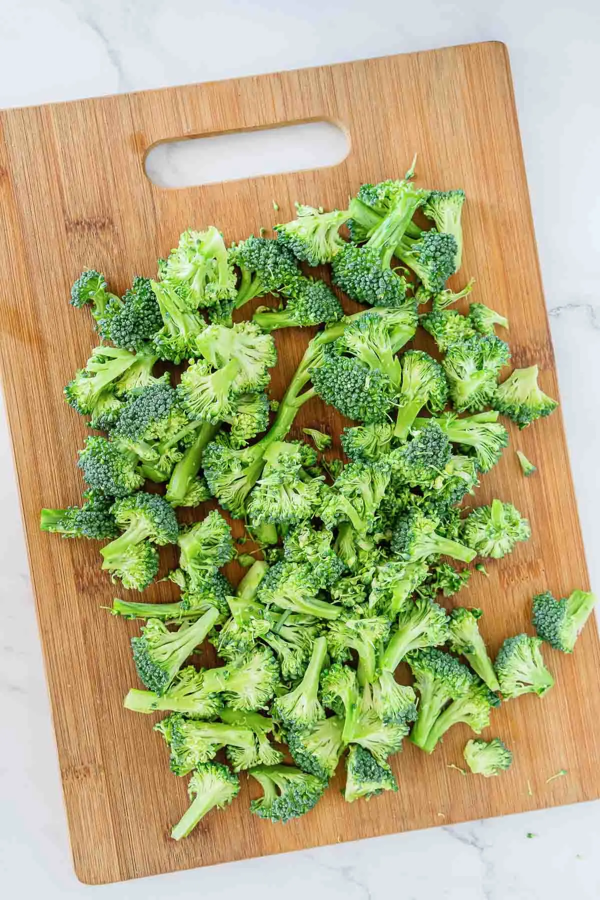 Broccoli florets cut into small pieces on a cutting board.