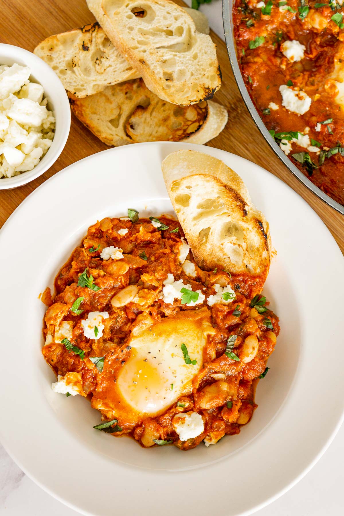 A plate of white bean shakshuka with feta with toasted bread.