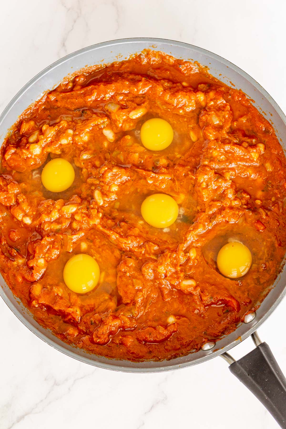 Eggs placed into a shakshuka pan.