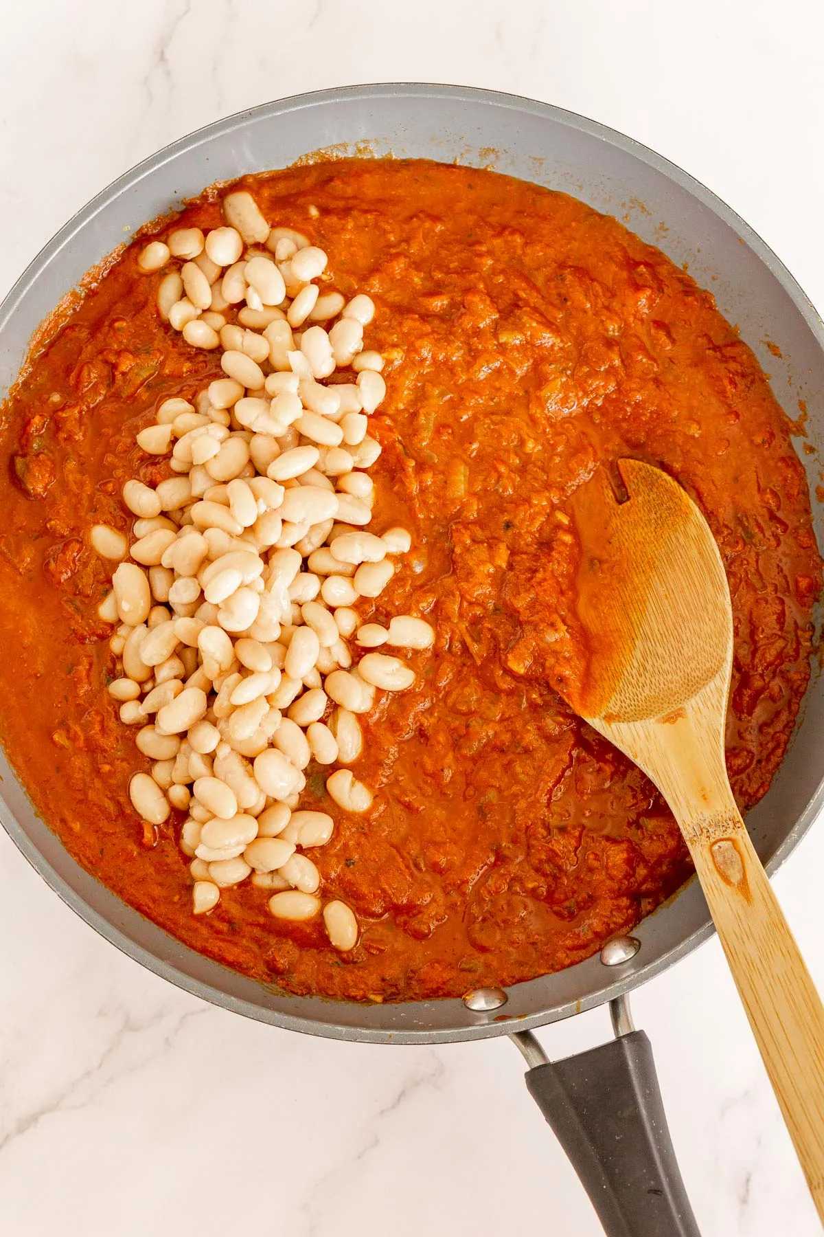 Spiced tomato sauce with white beans in a pan.