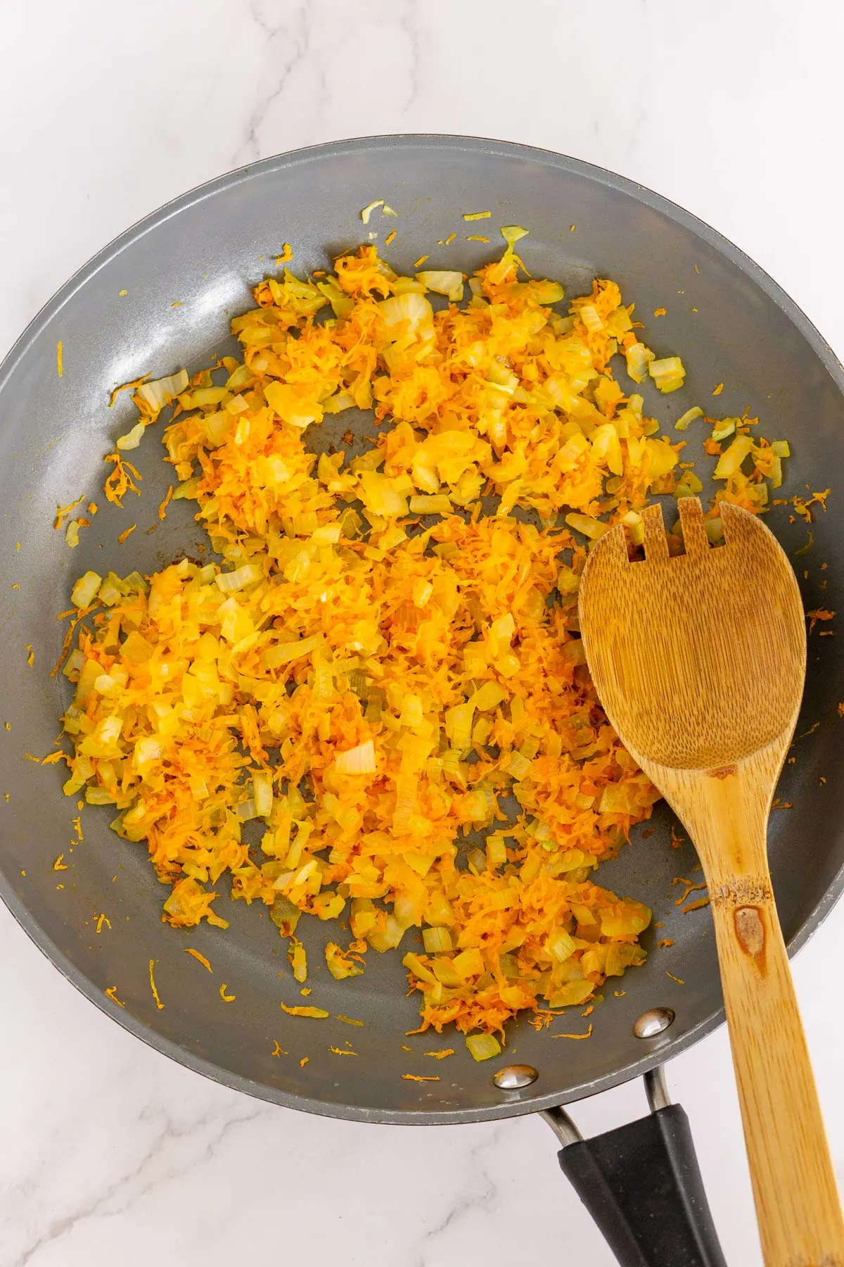 Sauteed carrot and onion in a pan.