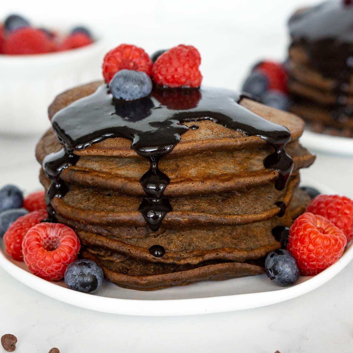 Stack of chocolate protein pancakes with chocolate sauce.