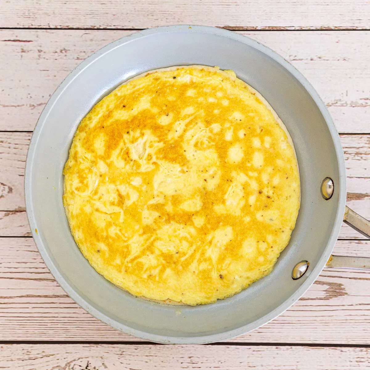 Scrambled egg and tortilla flipped in a pan.