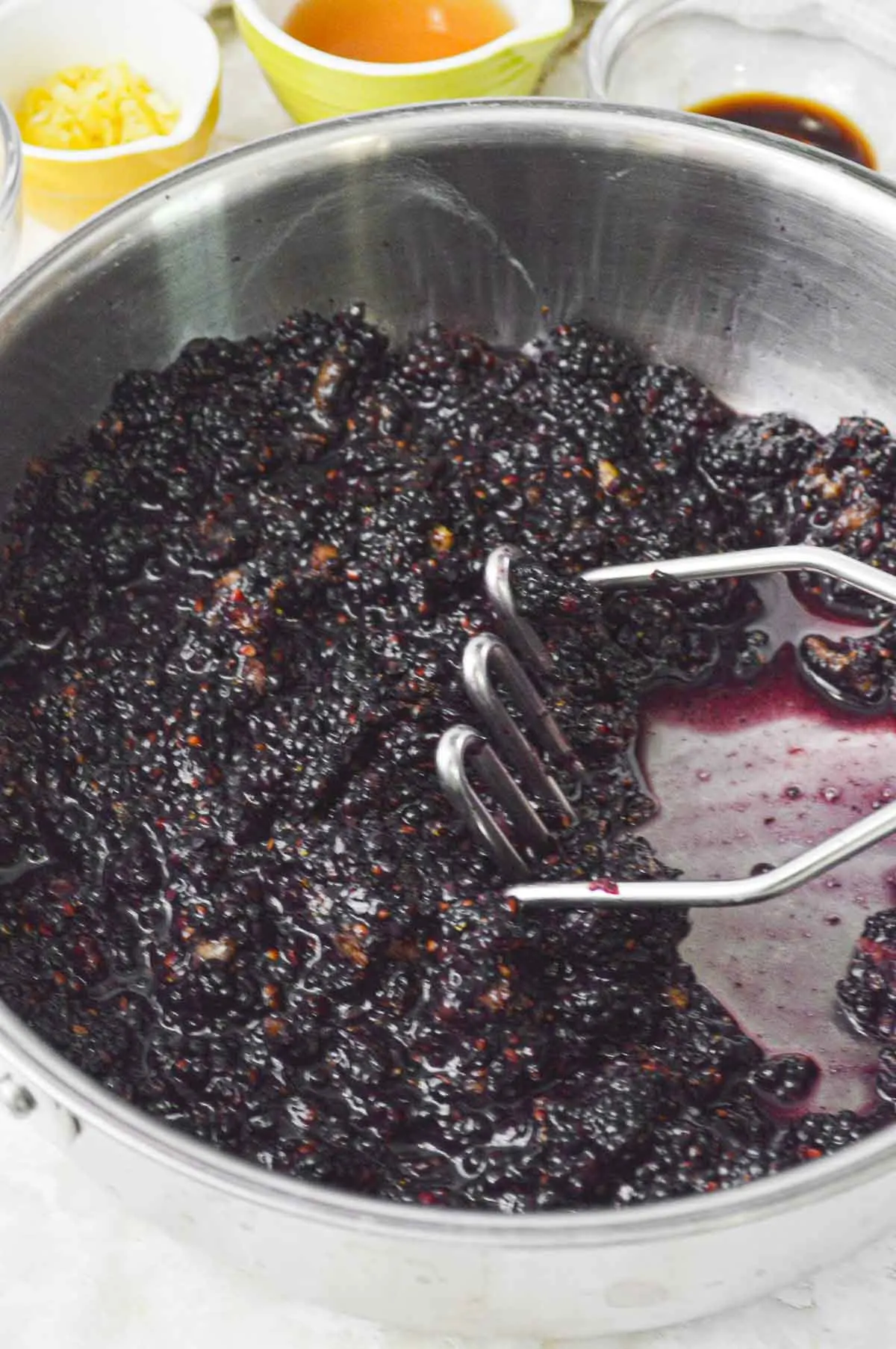 Mashing blackberries in a sauce pot.