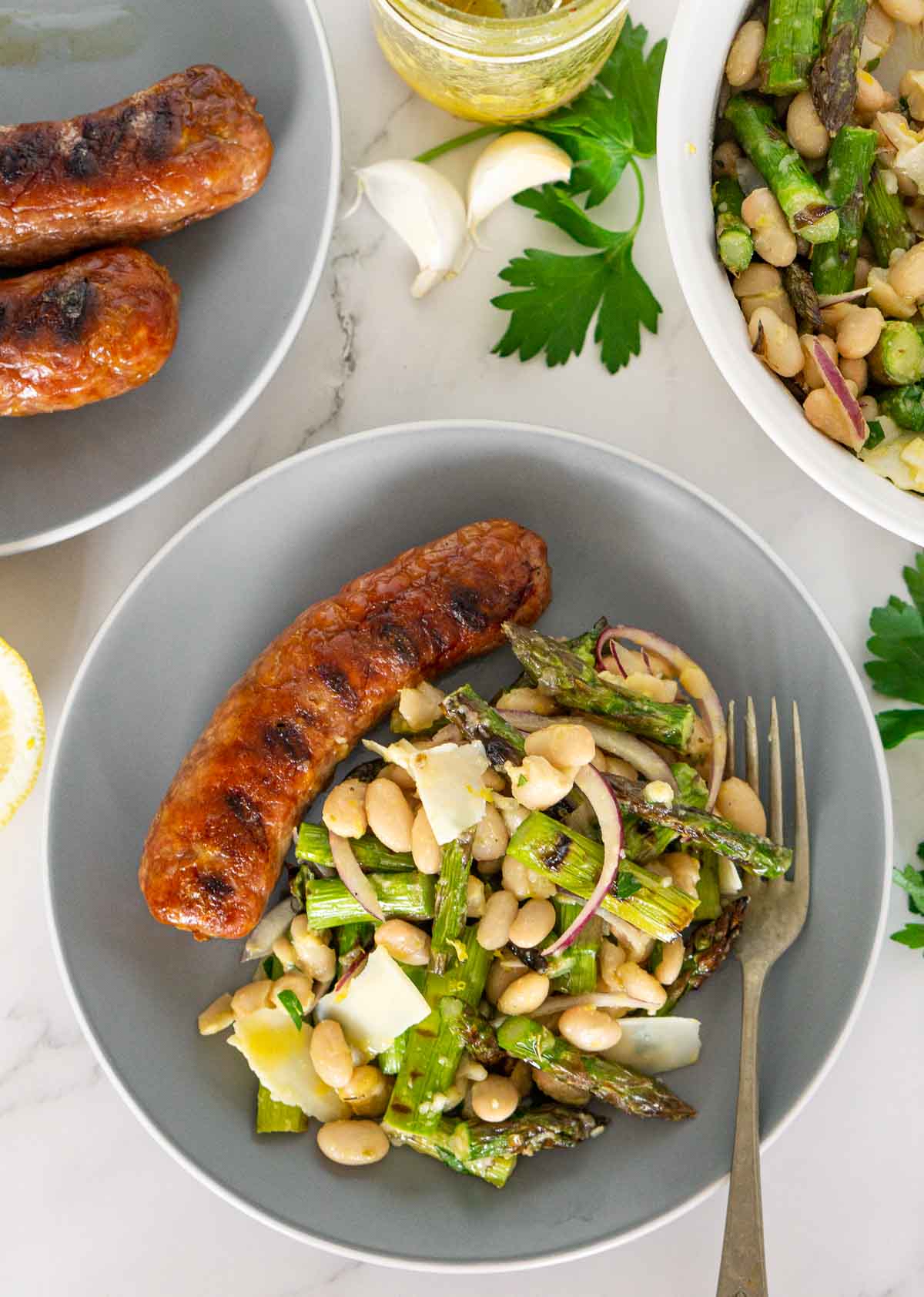 Plate of grilled sausage with grilled asparagus salad.