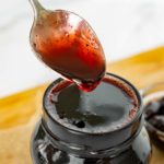 Cherry simple syrup on a spoon.