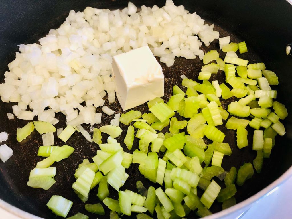 Sauteing chopped onion and celery in a pan with butter.