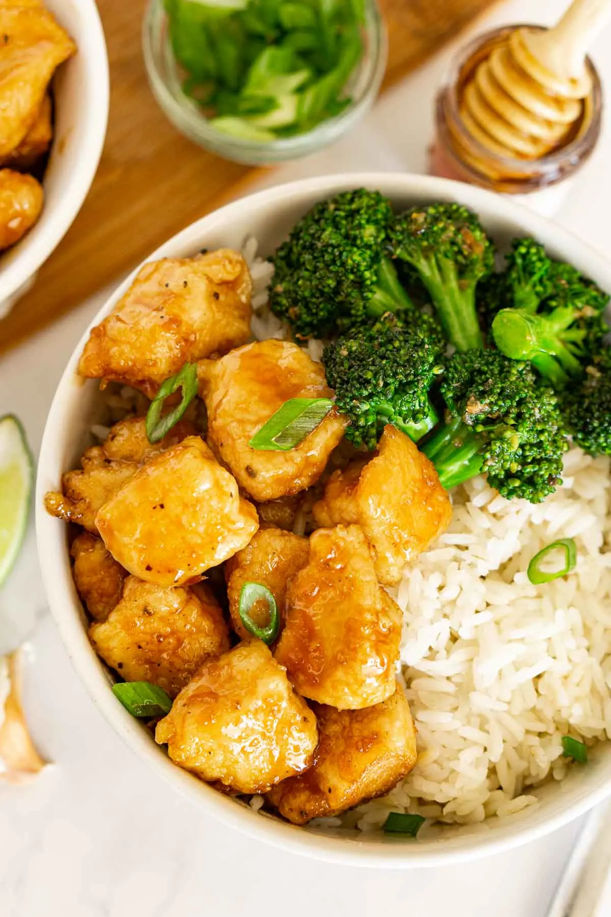 Bowl of hot honey chicken over rice with broccoli on the side.