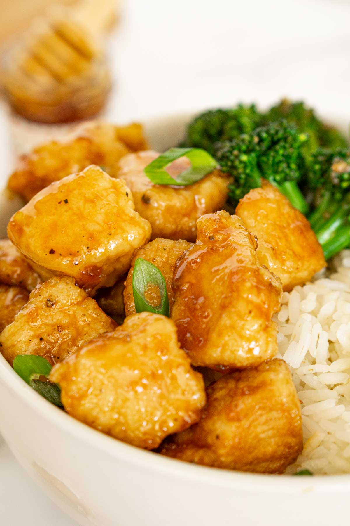 Closeup photo of hot honey chicken bites in a bowl of rice.