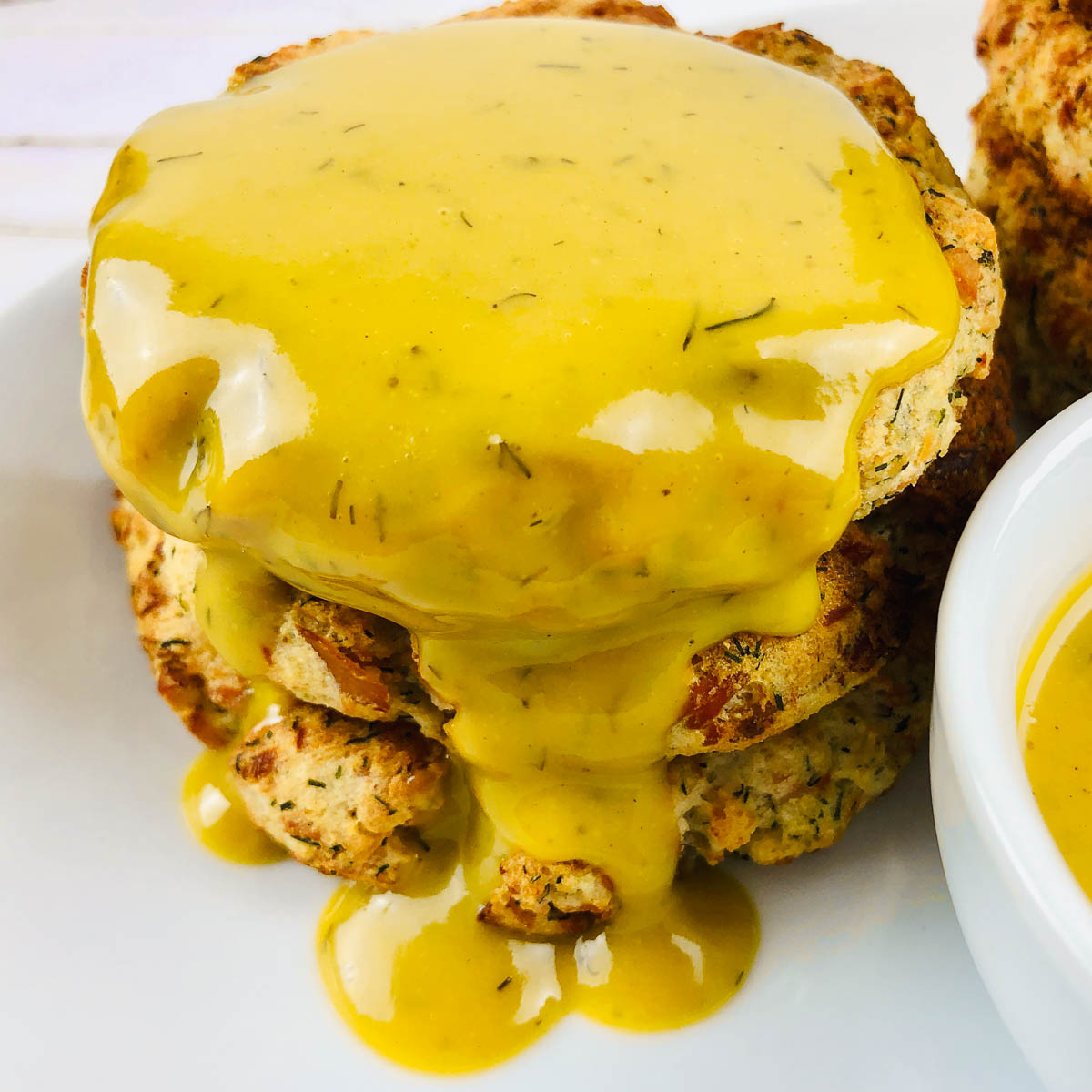 Stack of salmon potato cakes covered in honey mustard sauce.