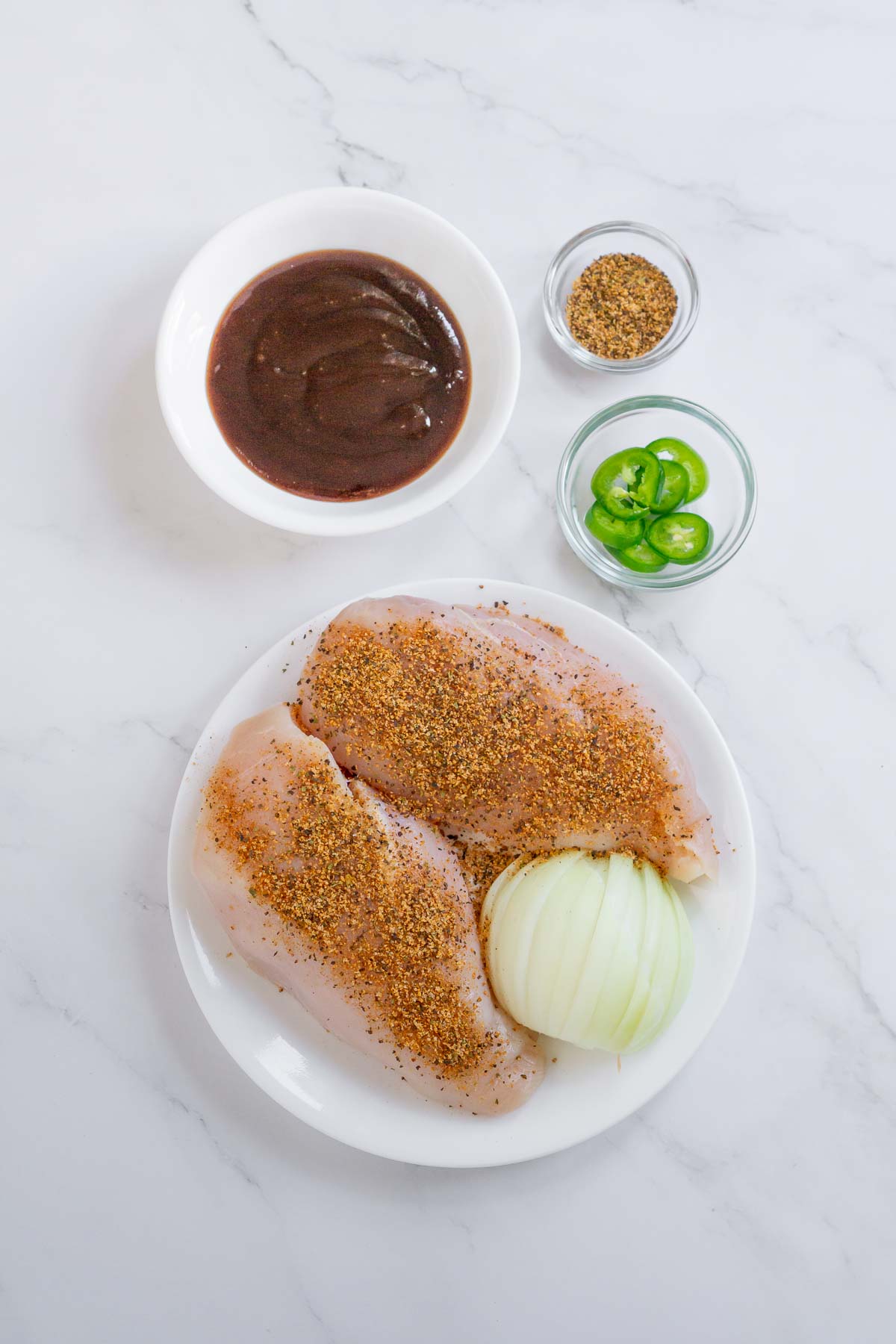 Ingredient to make sous vide shredded chicken: chicken breasts, BBQ sauce, seasoning, onion, and jalapenos.