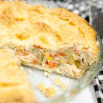 Pot pie made with leftover turkey in a pie dish, with a slice taken out.