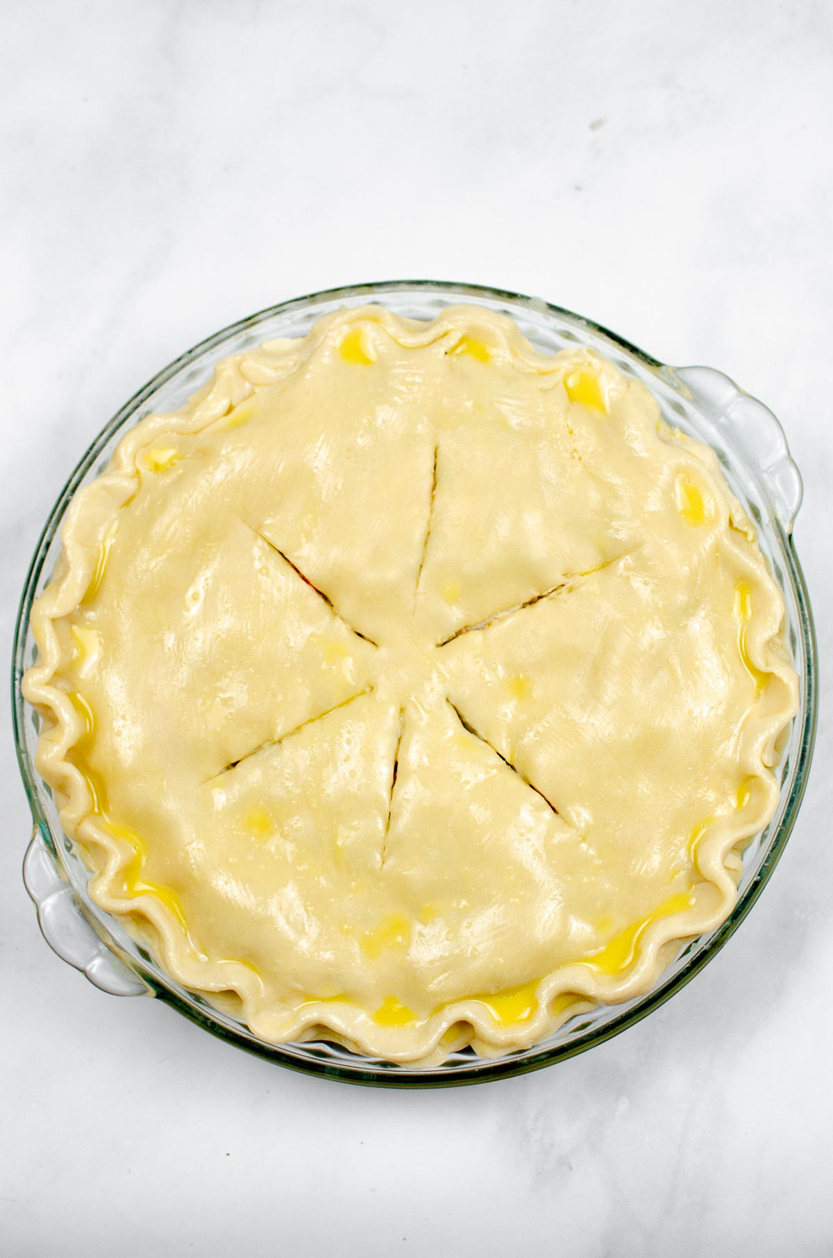 Uncooked turkey pot pie with the pie crust brushed with egg.