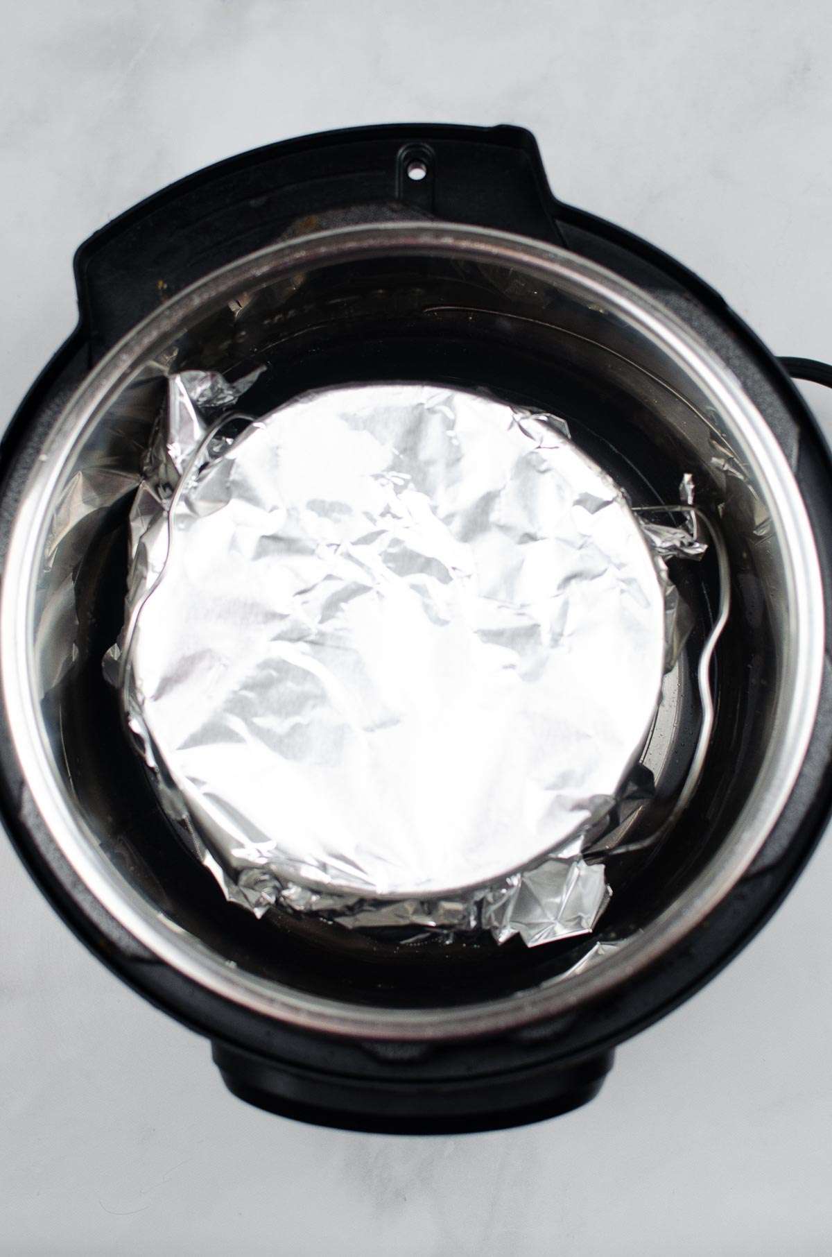 Springform Cake pan in an Instant Pot topped with foil.