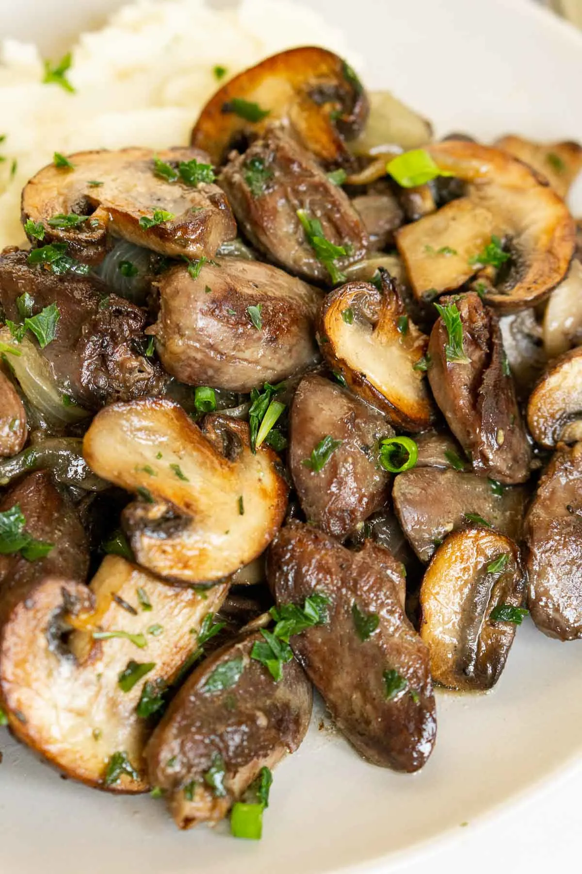Closeup picture of pan-fried chicken hearts with mushrooms.