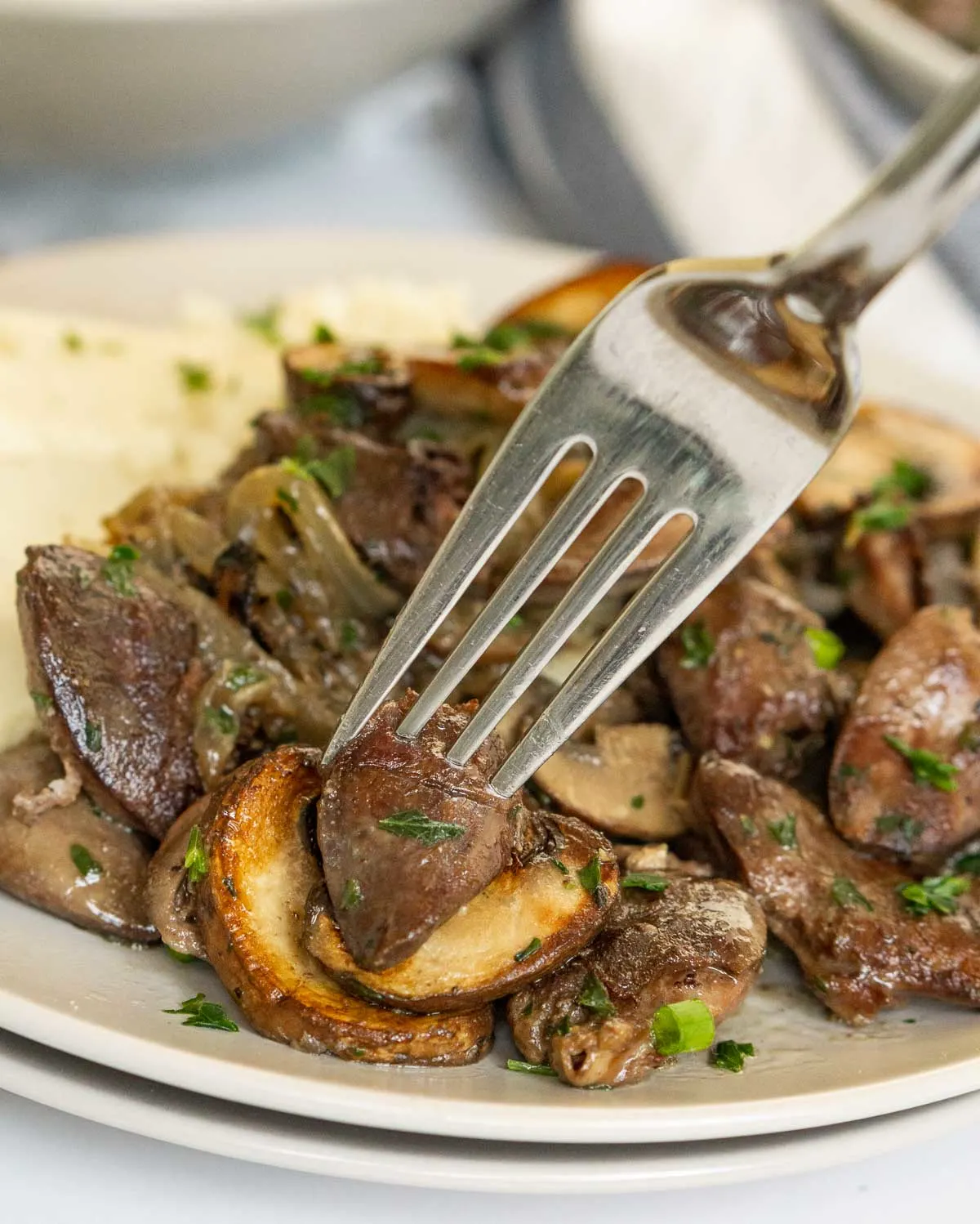 Sauteed chicken hearts with mushrooms on a plate with a fork.