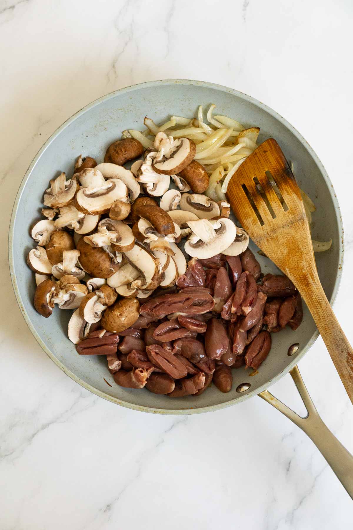 Skillet of sauteed onions, sliced mushrooms, and chicken hearts.