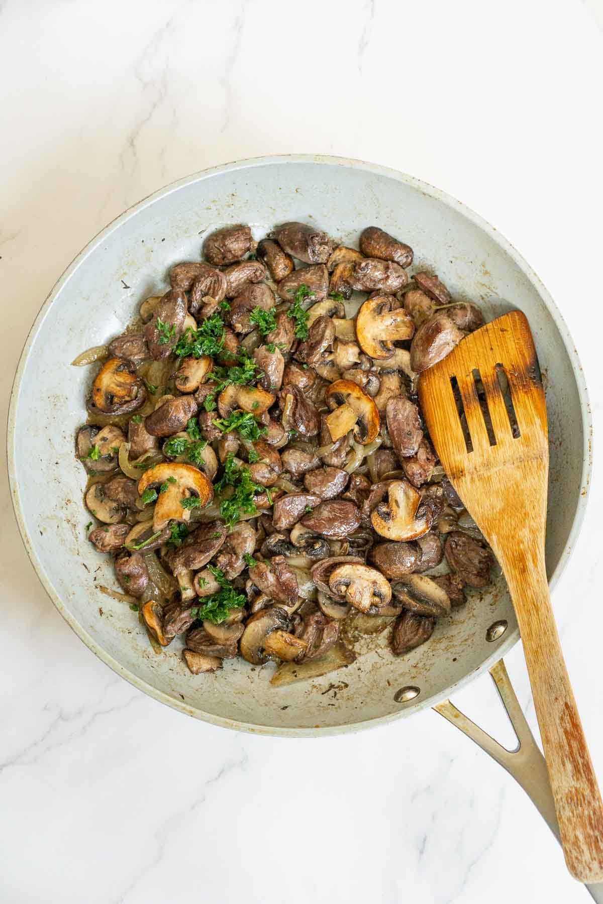 Chicken hearts and mushrooms on a skillet garnished with parsley.