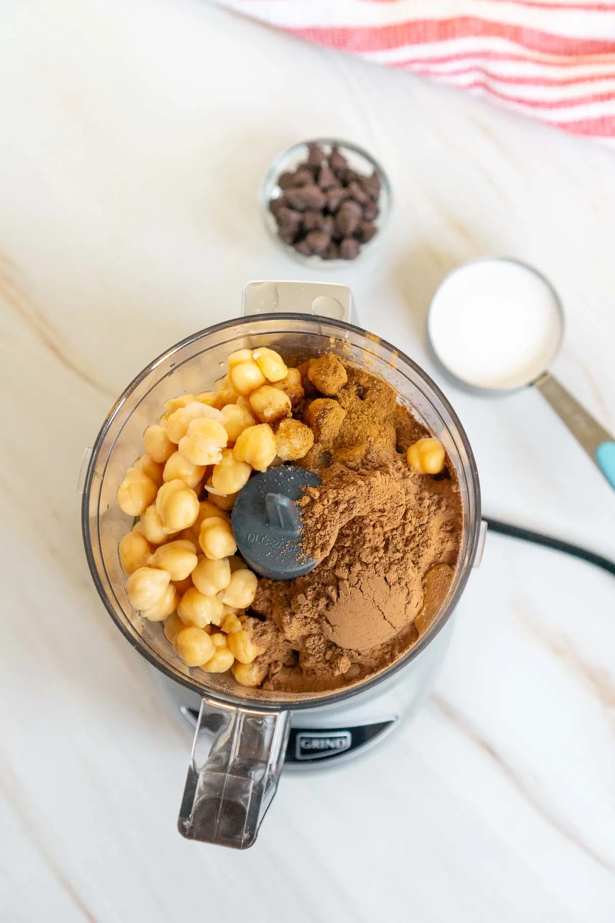 Chocolate hummus ingredients in a blender: chickpeas, cocoa powder, maple syrup, vanilla extract.
