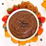 Bowl of chocolate hummus with a plate of strawberries, cookies, and crackers.