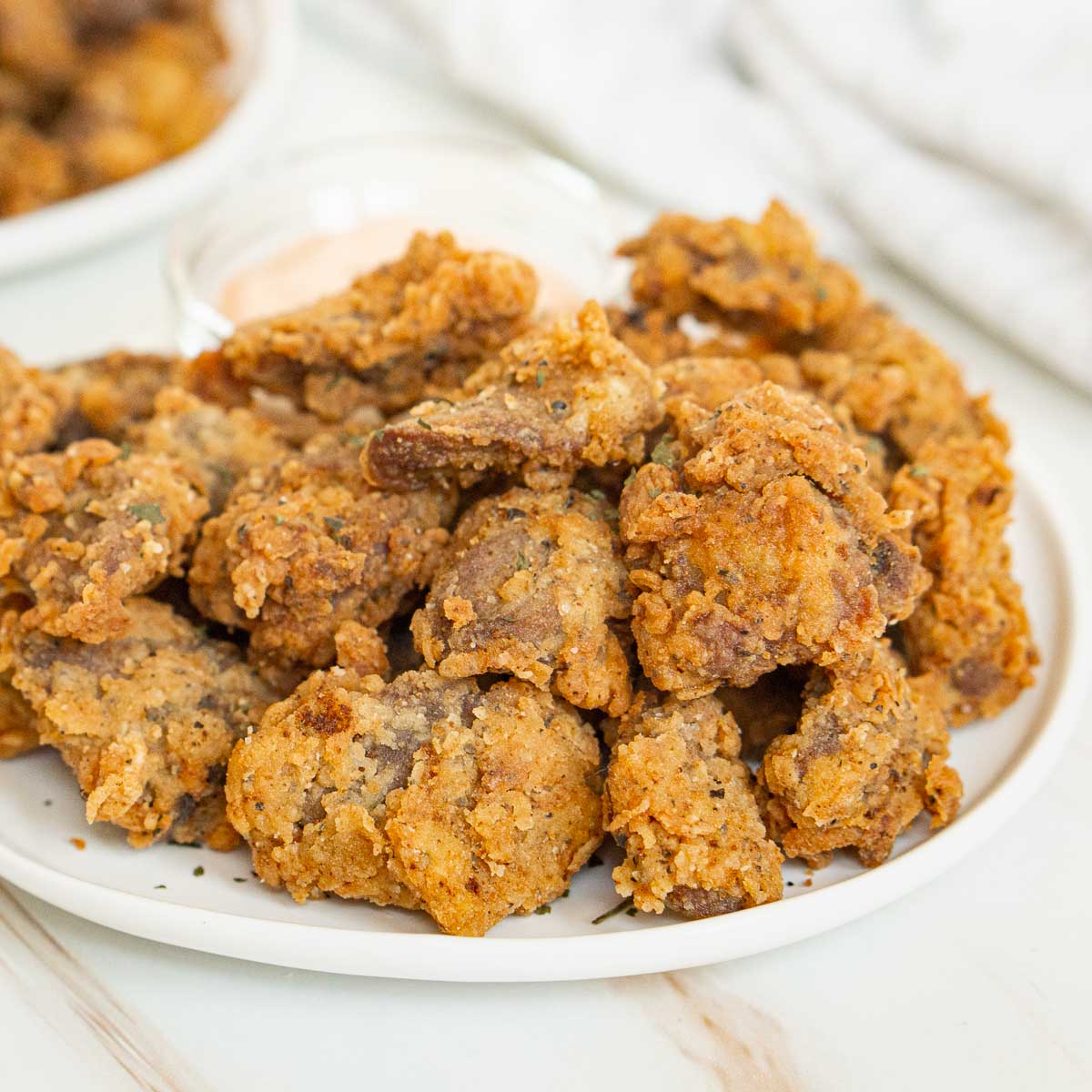 Plate of crispy fried chicken hearts with dip.