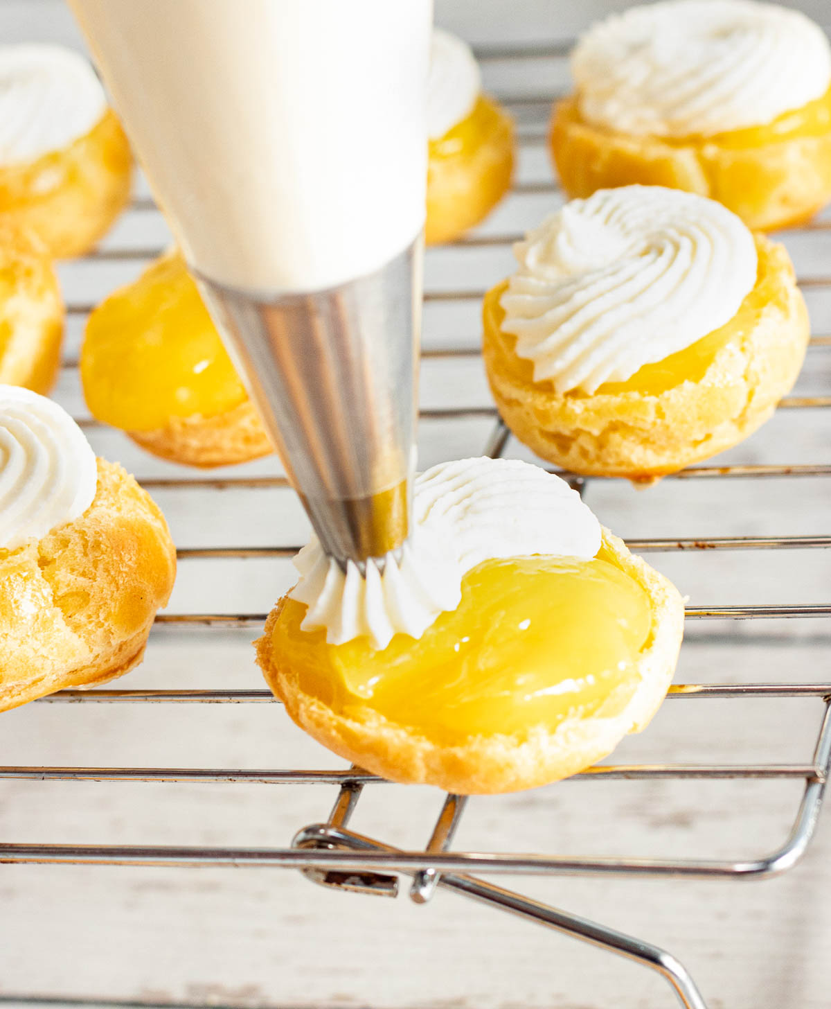 Piping cream cheese filling into cream puffs.