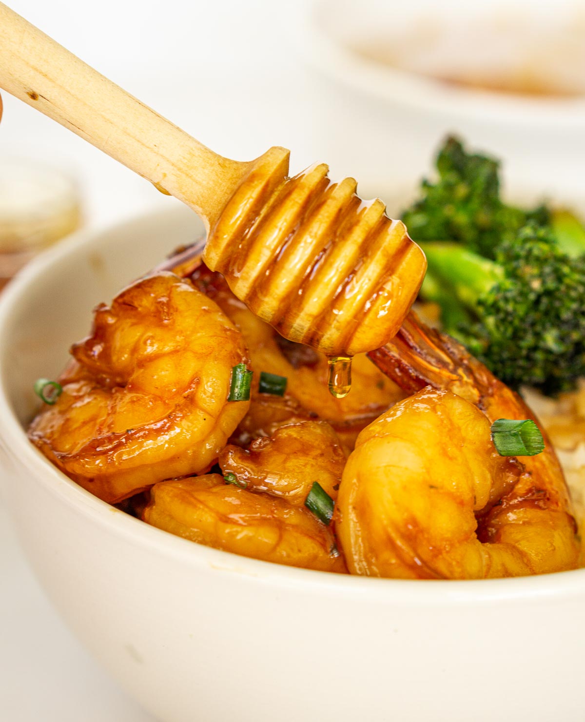 Drizzling honey on a bowl of spicy shrimp and broccoli.