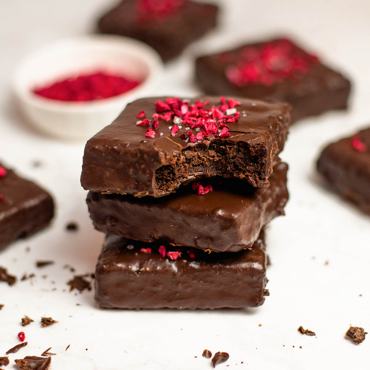 Stack of chocolate-covered brownies with freeze-dried raspberries.