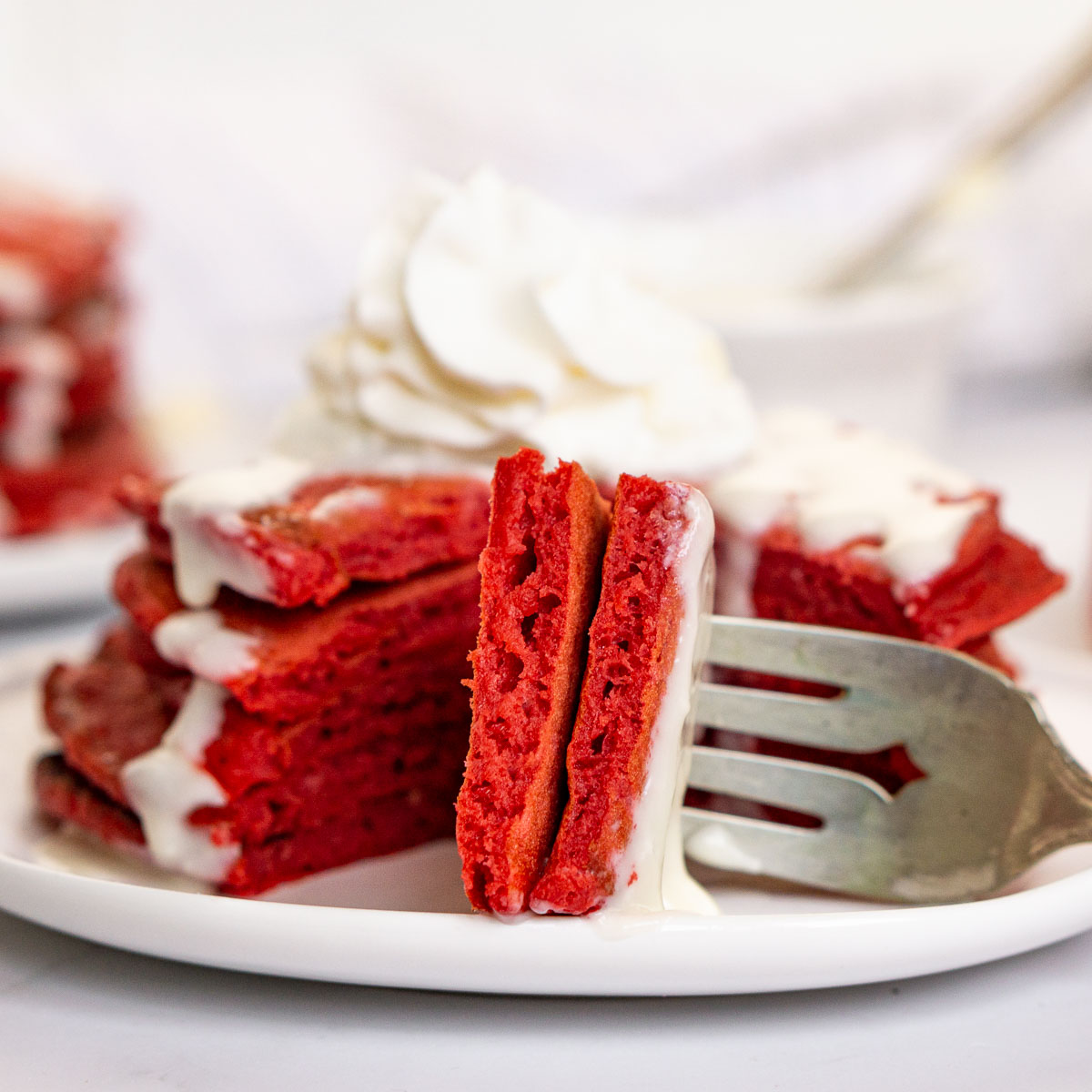 Stack of red velvet pancakes with a fork taking a piece out.