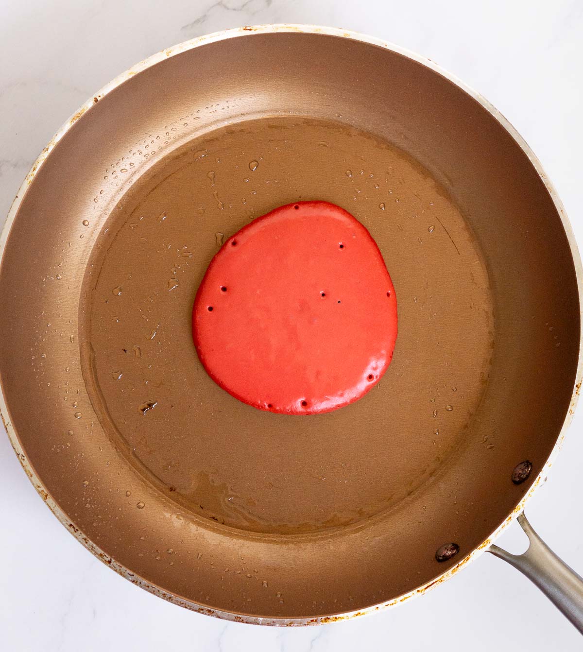 Red pancake cooking in a skillet.