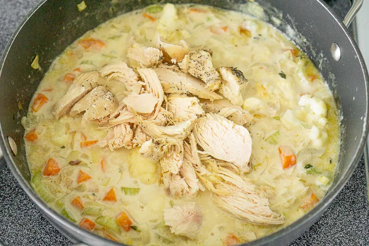 Adding chicken to creamy cauliflower soup