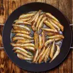 Anchovies frying in a skillet