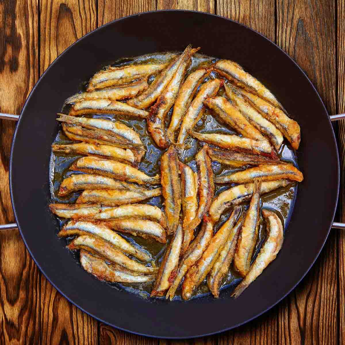 Anchovies frying in a skillet