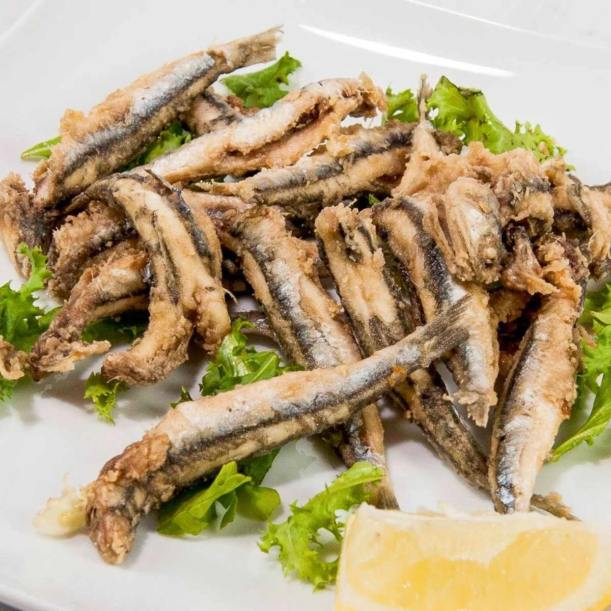 Plate of fried anchovies with lemon wedge