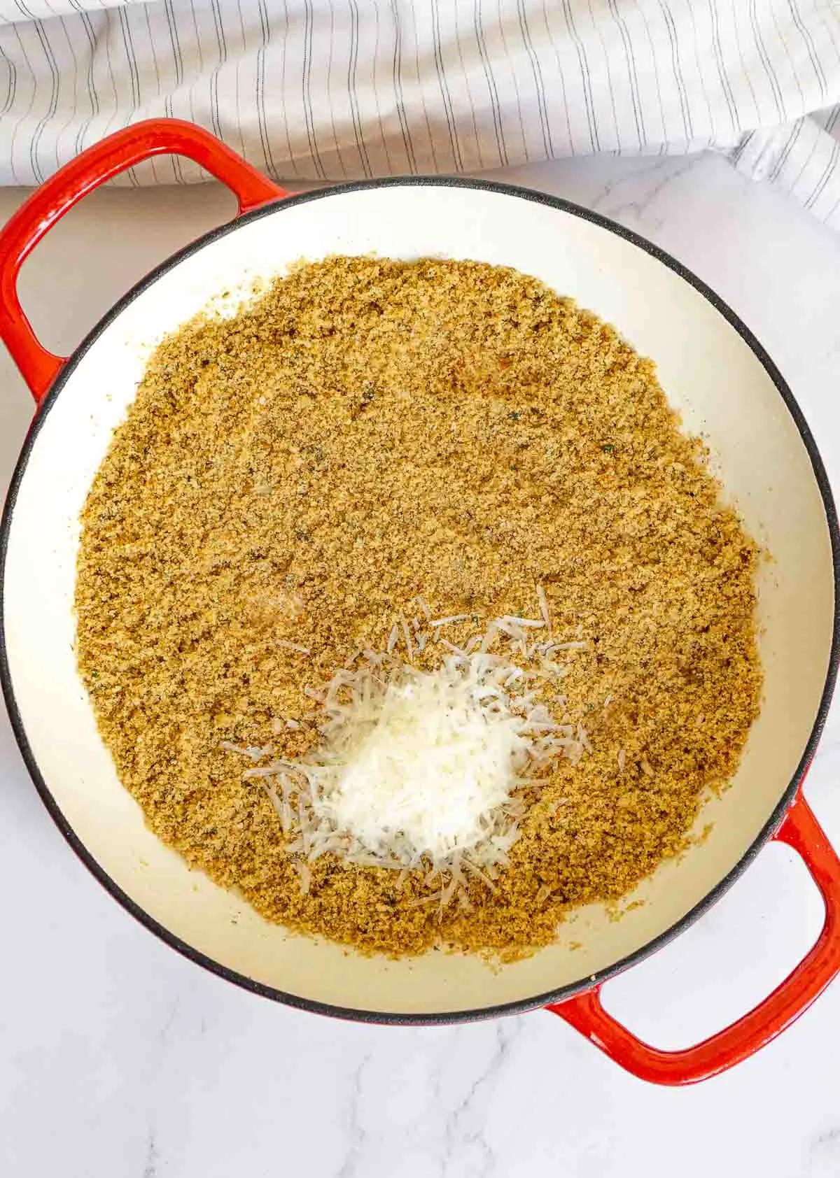 Toasted breadcrumbs in a pan with Pecorino-Romano cheese added.